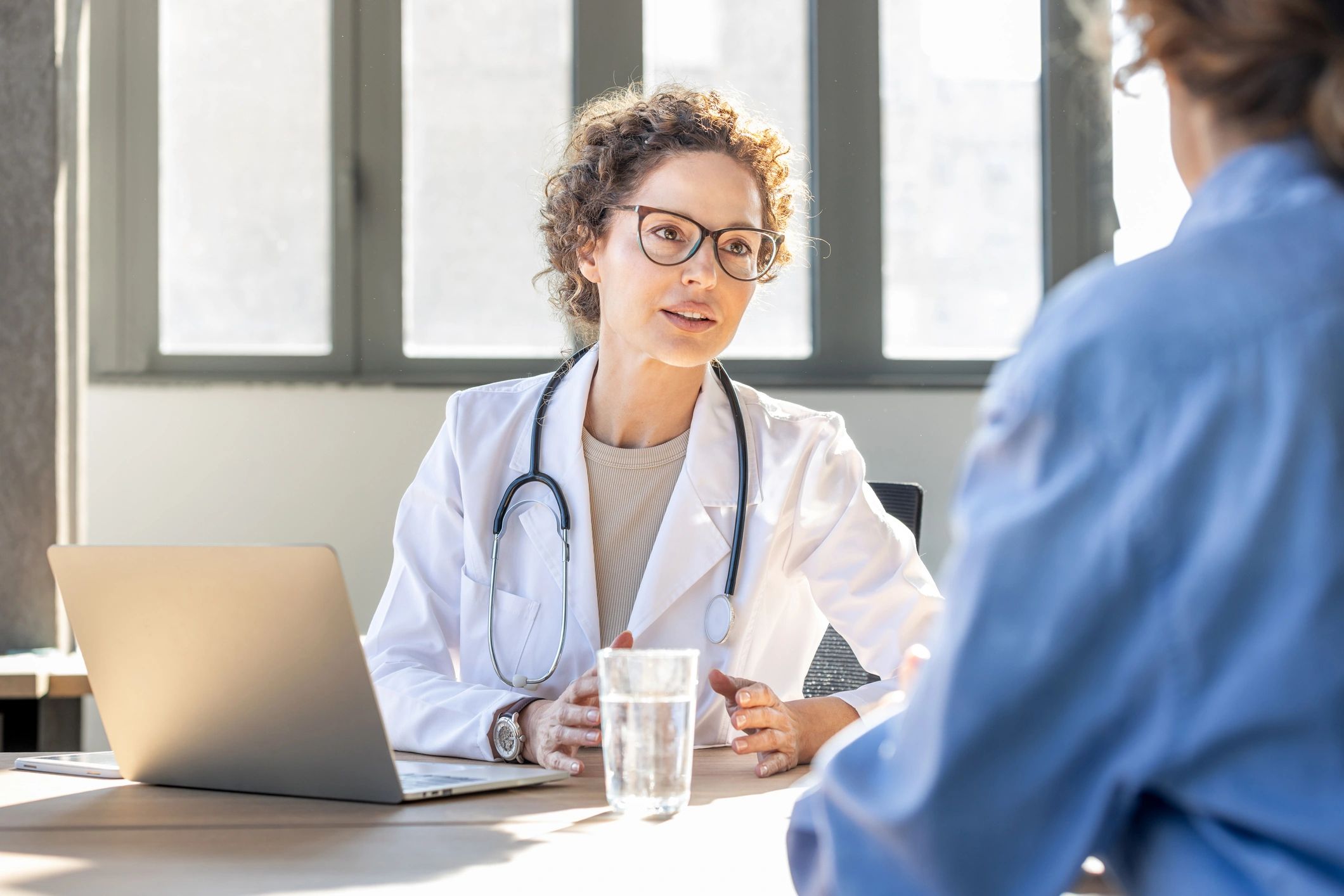 Doctor consulting with a patient using a laptop in a modern medical setting